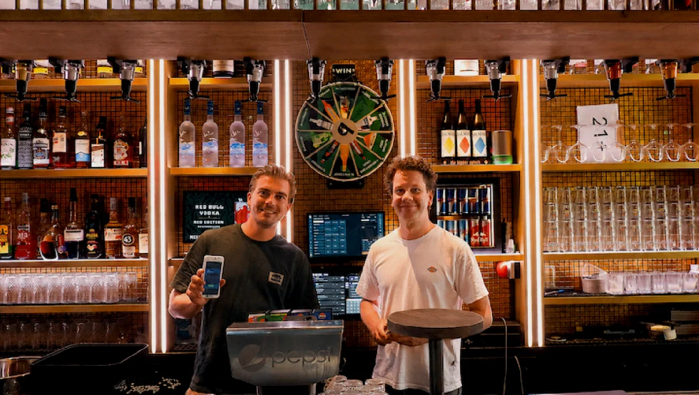 Ondernemer en adviseur achter de bar met handheld